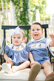 Baby girl and boy sitting together outdoors, boy wearing Ruth and Ralph Smocked Hunting Jon Jon with bow-topped sibling