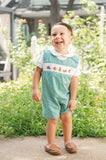 Toddler laughing in Smocked Camping Jon Jon by Ruth and Ralph, teal gingham with smocked camping embroidery, outdoors