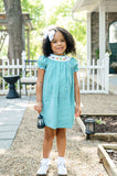 Girl standing outdoors in Ruth and Ralph Smocked Camping Dress, holding toy lantern, smiling