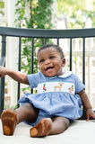 Close-up of baby smiling in Smocked Hunting Bubble by Ruth and Ralph, showing smocked deer and duck detail