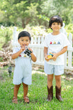 Close-up of two children in Ruth and Ralph smocked tractor outfits, showing embroidered tractor detail on both shirts