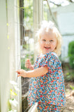 Baby girl smiling in doorway wearing Smocked Floral Pumpkin Bloomer Set by Ruth and Ralph, blue floral print with white bow