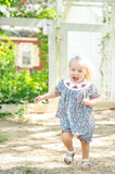 Baby girl running outdoors wearing Smocked Floral Pumpkin Bloomer Set by Ruth and Ralph, blue floral print
