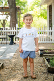 Boy wearing Ruth and Ralph Smocked Hunting T-Shirt and Short Set, standing on garden path outdoors