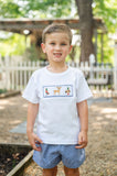 Boy wearing Smocked Hunting T-Shirt and Short Set by Ruth and Ralph, standing outdoors near white picket fence