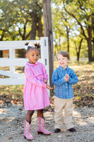 A little girl standing in the Pink Bandana Print Dress with pink boots looks absolutely adorable, blending sweet style with a playful western charm.