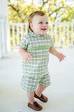 A toddler boy in a smocked Mardi Gras short set showcases the classic green, yellow, and purple plaid.