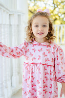 A little girl looks adorable in the Butterfly Heart Dress, featuring a soft light pink fabric with heart-shaped butterflies.