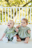 Two babies in a festive smocked bubble featuring classic Mardi Gras colors and plaid design