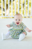 A baby in a charming smocked bubble with green, yellow, and purple plaid, perfect for Mardi Gras.