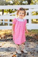 A little girl wearing the smocked Bandana and Boots Rodeo Helen Dress is ready for any special occasion, combining style and comfort effortlessly.