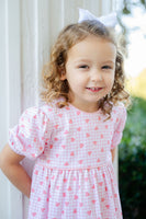 A young girl looks absolutely sweet in the Pink Pima Heart Dress, featuring a soft pink plaid pattern with heart accents.