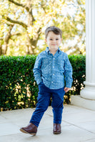 A little boy wearing the Blue Bandana Print Conrad Button-Up Shirt adds a touch of western charm to his wardrobe with this classic piece.