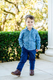 A little boy wearing the Blue Bandana Print Conrad Button-Up Shirt adds a touch of western charm to his wardrobe with this classic piece.