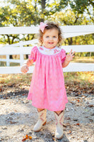 A little girl wearing the smocked Bandana and Boots Rodeo Helen Dress is sure to charm everyone with her adorable, tasteful outfit.