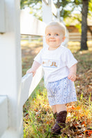 A little boy wearing the Boots and Bandanas Smocked Shirt and Shorts Set is ready for adventure with both style and comfort.