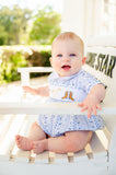 A little baby boy wearing the smocked Bandana and Boots Rodeo Henry Bubble in blue enjoys the softness of the fabric, perfect for all-day comfort.