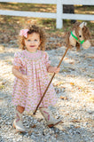 The Smocked Cowgirl Toile Helen Dress’s light pink color and playful western details make it perfect for everything from playdates to family photos.