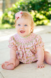 A baby girl wearing the Smocked Cowgirl Toile Birdie Bubble looks absolutely adorable in this western-inspired outfit.