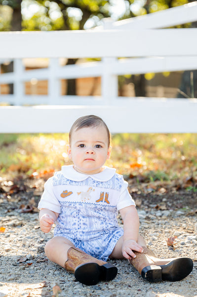 A little boy sitting and wearing the Bandana and Boots Rodeo Benjamin Jonjon looks adorable in this charming, smocked outfit.