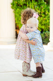 A little boy wearing the Smocked Cowboy Toile Samuel Shirt/Shorts Set is sure to capture attention with its fun cowboy toile print and stylish design.