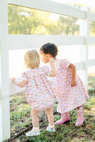 A toddler girl wearing the Pink Cowgirl Toile Pima Hallie Bubble will love its light pink color and fun cowgirl toile print.