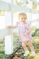 A baby girl wearing the Pink Cowgirl Toile Pima Hallie Bubble looks absolutely adorable in this soft, pink outfit with charming western details.