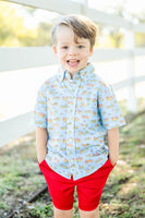 A little boy wearing the Blue Cowboy Toile Conrad Button-Up Shirt looks charming in this western-inspired shirt with a blue background.