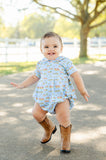 A toddler boy wearing the Blue Cowboy Toile Pima Alexander Bubble looks absolutely adorable in this charming outfit with a cowboy toile print.