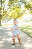 A toddler boy wearing the Blue Cowboy Toile Pima Alexander Bubble is ready for playdates or family photos with its stylish western-inspired print.