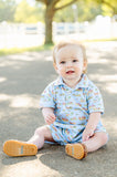 A toddler boy wearing the Blue Cowboy Toile Pima Harold Romper is ready for adventure with its fun, western-inspired details.