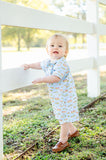 A toddler boy wearing the Blue Cowboy Toile Pima Harold Romper looks absolutely charming in this western-inspired outfit.