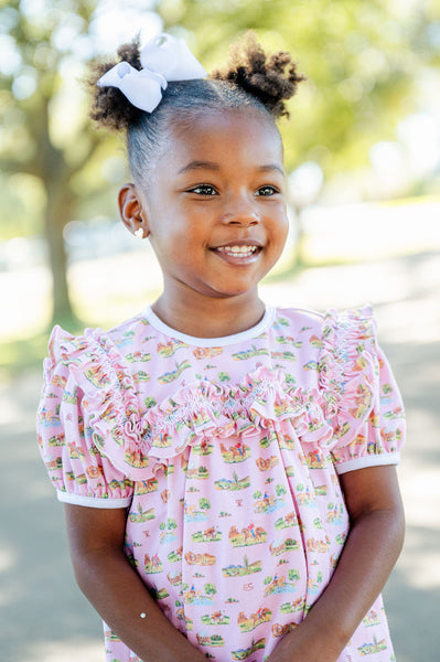 A girl wearing the Pink Cowgirl Toile Pima Mary Bloomer Set looks adorable in this soft, comfortable outfit with a pink background.