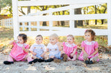 A little girl wearing the Smocked Pink Bandana and Boots Rodeo Annabelle Bloomer Set looks adorable with its playful bandana print and cute bloomer shorts, perfect for a casual, stylish outing.