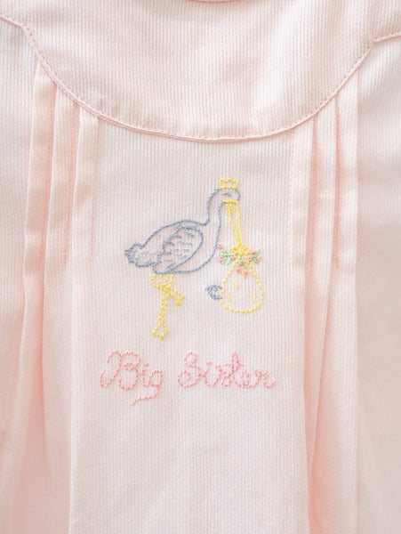 The lace-trimmed sleeves add a touch of sweetness to the Big Sister Stork Dress in pink.