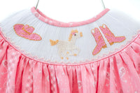 The set features a smocked top with a fun pink bandana print and boot accents, creating a charming and stylish look.