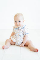 A little toddler boy wearing the Puppies Pima Bubble with blue piping looks absolutely charming, featuring playful puppy details on the bodice.