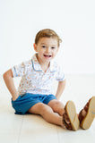 A toddler boy enjoys a sunny day in the Puppies Pima Short Set with blue piping and blue shorts, staying cool and comfortable.