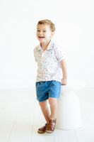 A little boy wearing the Puppies Pima Short Set with blue piping and blue shorts looks stylish and ready for spring.