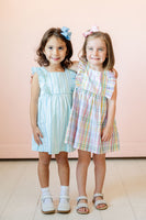 A little girl wearing the Blue Striped Dress will love the sweet ruffle details that add a playful touch.