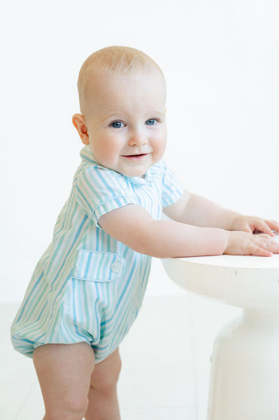 A little baby boy looks absolutely adorable in the Blue Striped Bubble with a Peter Pan collar, perfect for a sunny spring day.