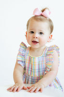 A baby girl wearing the Colorful Plaid Bubble looks adorable in its cheerful, spring-inspired plaid pattern.