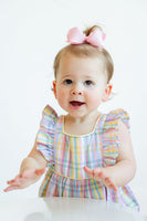 A baby girl wearing the Colorful Plaid Bubble in vibrant spring colors is ready for sunny outings and fun adventures.