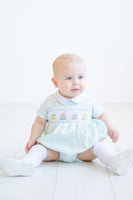 Dressed in the smocked mint green birthday cake bubble, a little boy is all smiles at his birthday party.