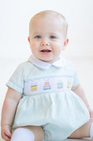 A little boy looks adorable in the smocked mint green birthday cake bubble, ready to celebrate his special day.