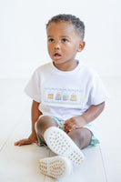 Dressed in a smocked birthday cake T-shirt and mint green shorts, a little boy is all set for party fun.