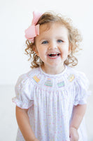 Dressed in the smocked sprinkle birthday cake dress, a little girl is ready to shine at her birthday celebration.