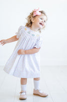 A little girl looks picture-perfect in her smocked sprinkle birthday cake dress, ideal for celebrating with family and friends.