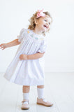 A little girl looks picture-perfect in her smocked sprinkle birthday cake dress, ideal for celebrating with family and friends.