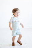 A little boy enjoys his party in a smocked mint green jonjon, featuring sweet birthday cake details and timeless charm.